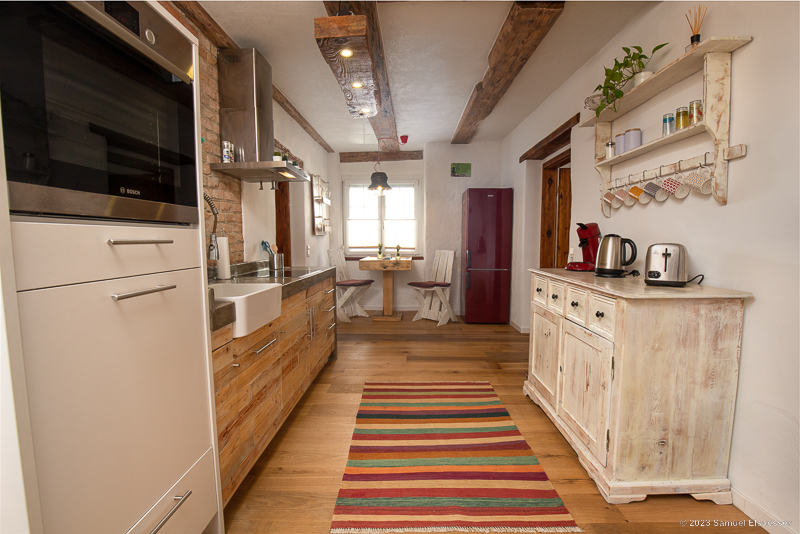 Der zentrale Aufenthaltsbereich ist der Flur, mit der hervorragend integrierter Küche und einem kleinen gemütlich Frühstückstisch.